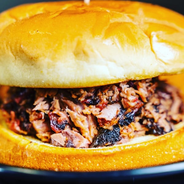 Close-up of a Fat Floyd's Barbecue pulled pork sandwich on a golden bun.